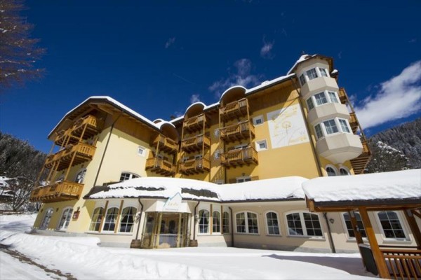 Žlutá budova hotelu pod modrou oblohou, obklopená sněhem.