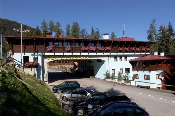 Horský hotel s dřevěnými prvky a květinami na balkonech.