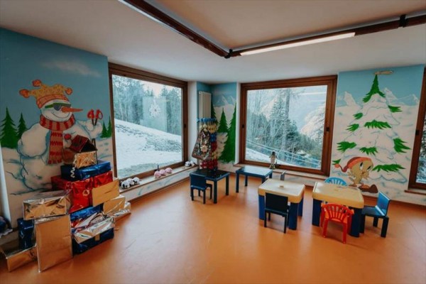 Dětská herna s vánoční výzdobou, obrázky sněhuláka a stromků na stěnách.