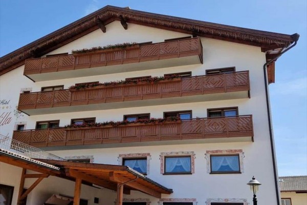Budova s dřevěnými balkóny a dekorativními okny.