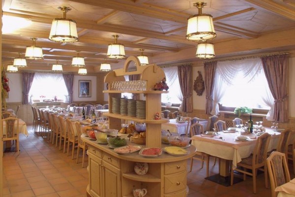 Uspořádaná restaurace s prostřenými stoly a bufetem s jídlem uprostřed.