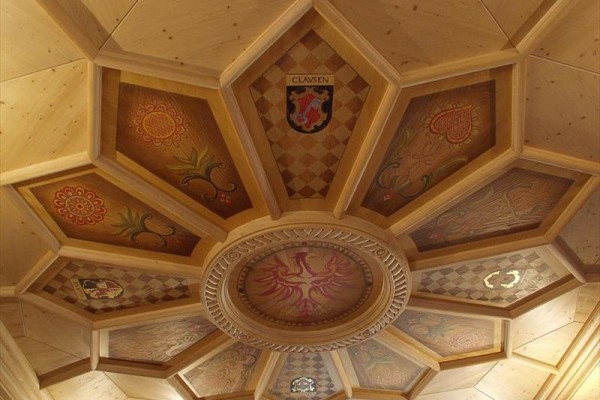 Dřevěný strop s geometrickým vzorem a zdobenými panely.