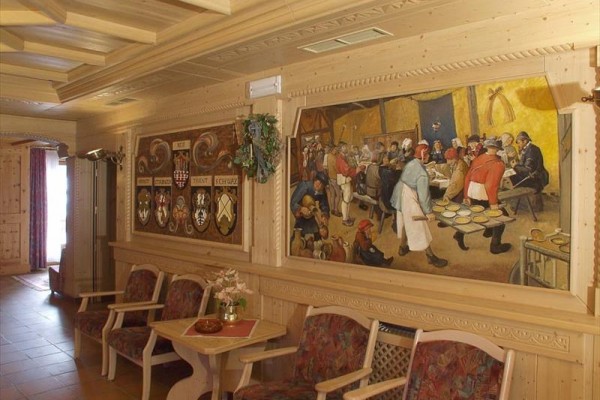 Interiér místnosti se zdobeným dřevěným obložením a nástěnnou malbou.