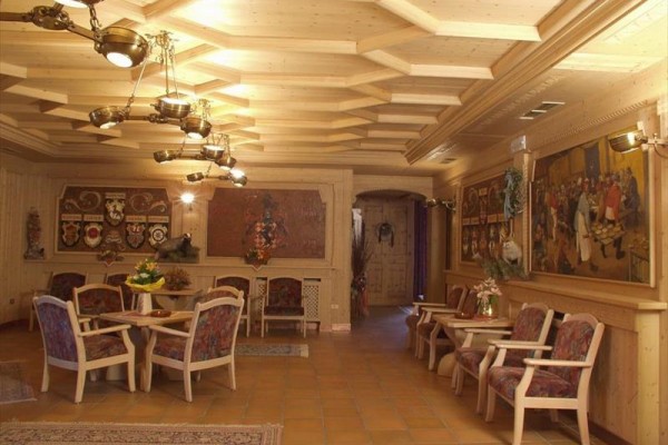 Elegantní dřevěný interiér s několika stoly a obrazy na stěnách.