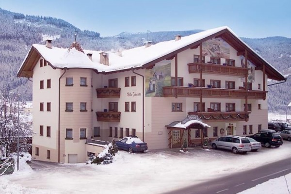 Horsky hotel se zasněženou střechou a výhledem na zasněžené hory.