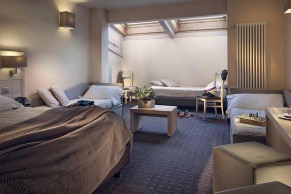 Moderní hotelový pokoj se třemi lůžky a světlým designem.