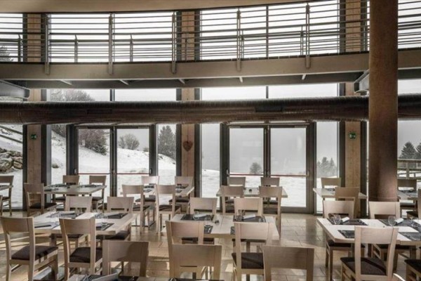 Interiér restaurace s výhledem na zasněženou krajinu.
