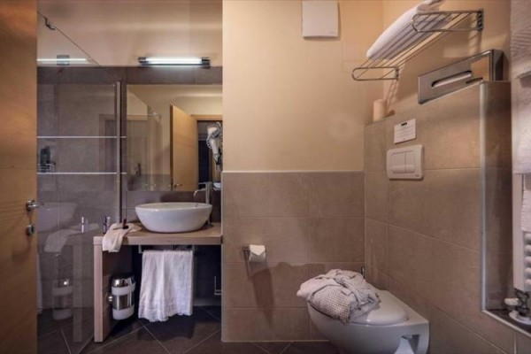 Moderní koupelna s umyvadlem, sprchovým koutem a toaletou ve světlých tónech.
