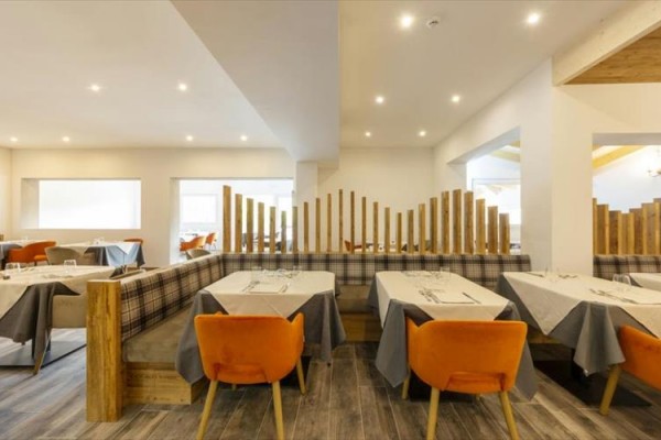Moderní restaurace s dřevěnou výzdobou a oranžovými židlemi.