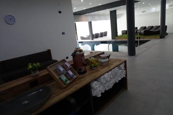 Moderní wellness prostor s bazénem a odpočinkovými lehátky.