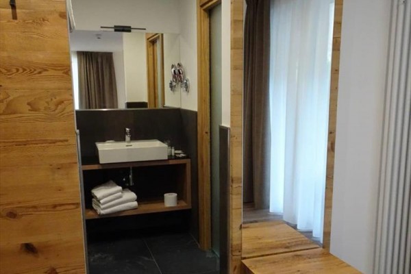 Koupelna s umyvadlem na dřevěné desce, skříňkou a zrcadlem.