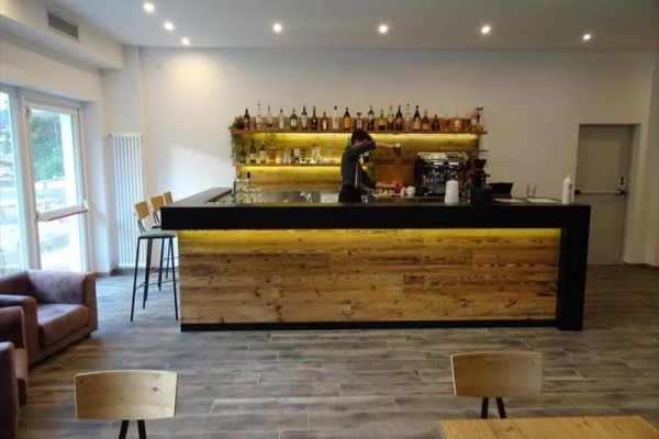 Moderní bar s barmanem připravujícím nápoj před policí plnou lahví alkoholu.