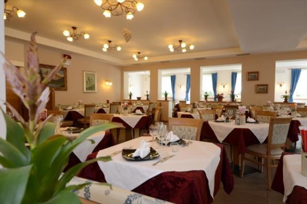 Elegantně prostřená restaurace s bílými ubrusy a květinovou výzdobou.