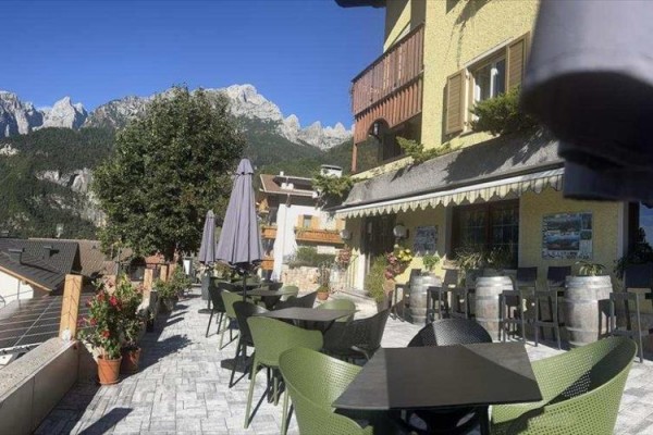 Terasa restaurace s výhledem na horský masiv za slunečného dne.
