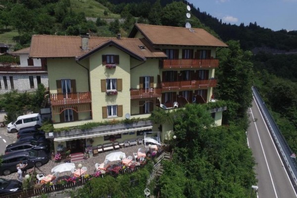 Budova hotelu se žlutou fasádou a balkony se nachází v kopcovité krajině vedle silnice.
