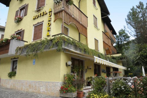 Žlutý hotel se zahradou a terasami obklopený rostlinami.
