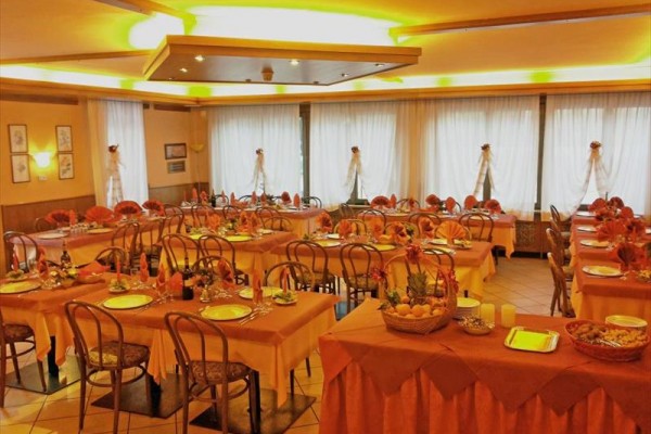 Restaurace s prostřenými stoly a oranžovou dekorací připravená pro hosty.