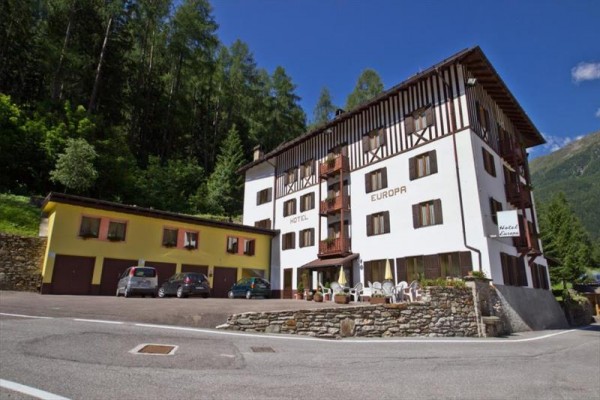 Hotel Europa s parkovištěm, obklopený lesy a horami.