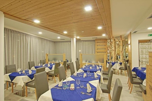 Restaurace s dřevěným stropem, modrými ubrusy a šedými židlemi.