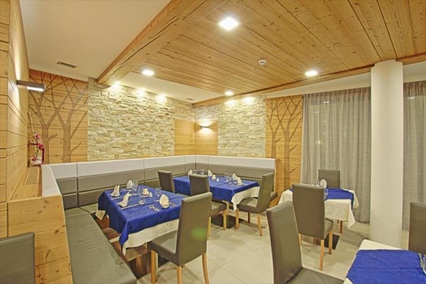 Moderní restaurace se dřevěným obložením a připravenými stoly s modrými ubrusy.