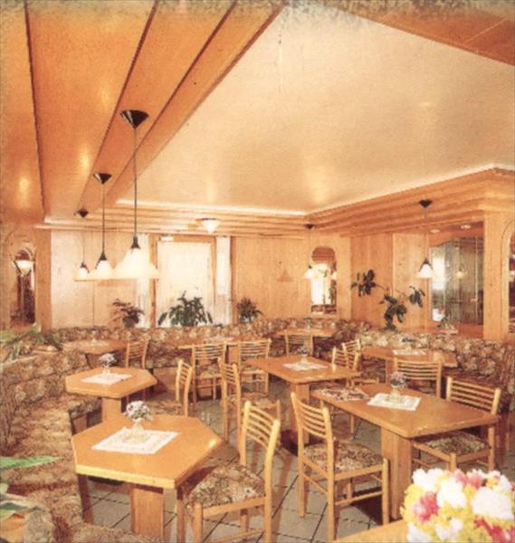 Restaurace s dřevěným interiérem, stoly, židlemi a květinami.