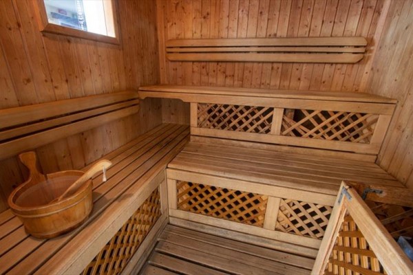 Dřevěná sauna s lavicemi a vědrem.
