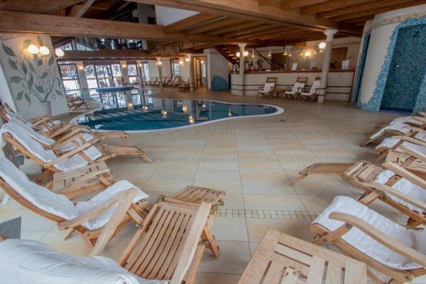 Relaxační místnost s bazénem a dřevěnými lehátky kolem.