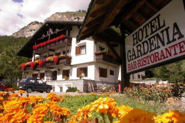 Hotel Gardenia s květinovou výzdobou a horskou scenérií v pozadí.
