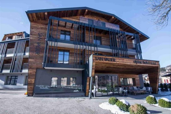 Moderní horský hotel s dřevěným obložením a balkony.