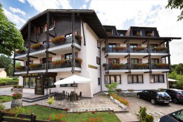 Hotel s dřevěnými balkóny zdobenými květinami a venkovní terasou.