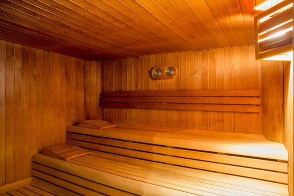Dřevěná sauna se dvěma lavicemi a teploměrem na stěně.
