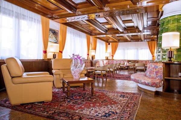 Elegantní hotelový salonek s pohovkami a bohatým dřevěným obložením.