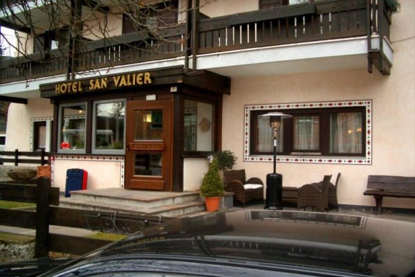Vchod do hotelu San Valier s lavičkami a květináčem před ním.
