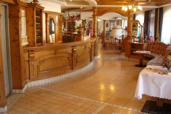 Tradiční dřevěný interiér restaurace s barovým pultem a jídelním koutem.