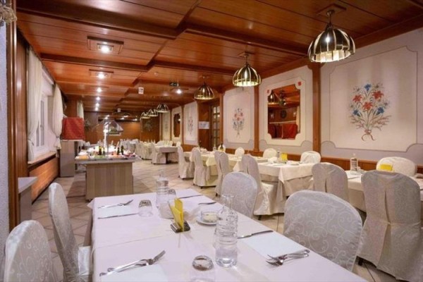 Stylová restaurace s dřevěným obložením a stolem připraveným k večeři.  