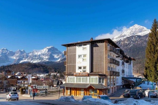 Hotel v horské oblasti s zasněženými vrcholky na pozadí.