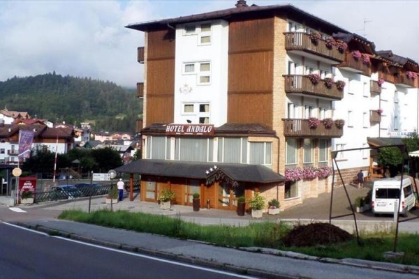Hotel Andalo s květinami na balkonech a horami v pozadí.