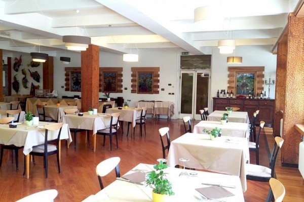 Světlá restaurace s dřevěnou podlahou a stoly připravenými k servírování.