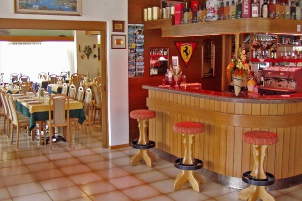 Interiér restaurace s dřevěným barem a vedlejším jídelním prostorem s prostřenými stoly.