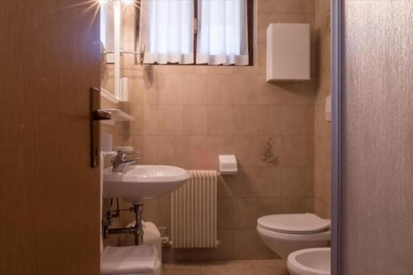 Malá koupelna s umyvadlem, toaletou a topením.