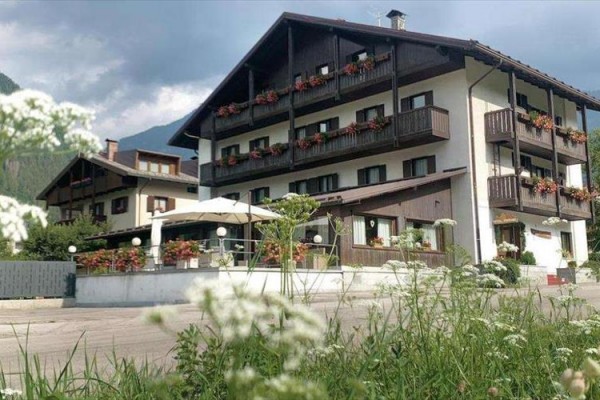 Horský hotel s dřevěnými balkony a květinovou výzdobou podél oken.