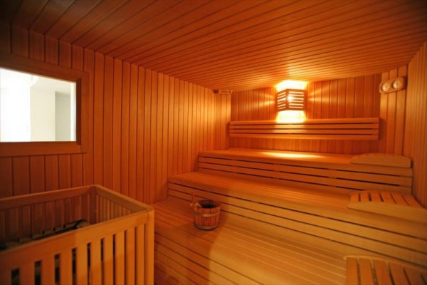 Dřevěná sauna s lavicemi a vědrem na vodu.