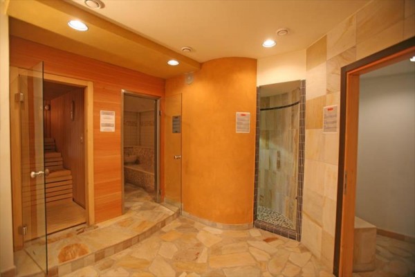 Sauna s dřevěným interiérem a přilehlou sprchou.