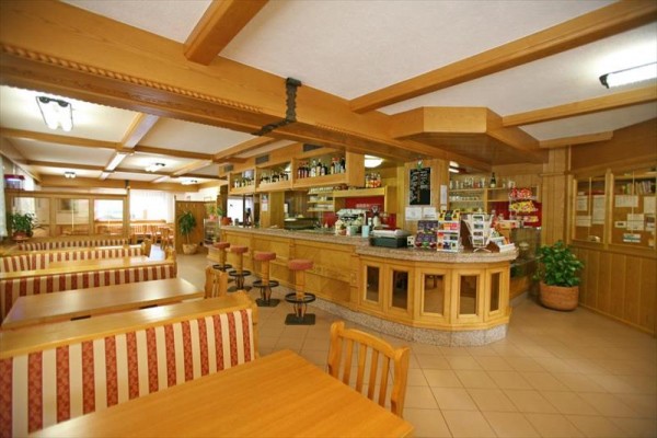 Interiér restaurace s dřevěnými lavicemi a barem.