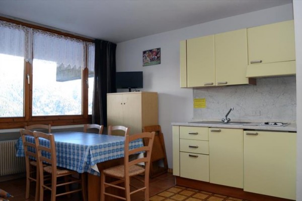 Kuchyň s jídelním stolem, židlemi a kuchyňskou linkou v béžové barvě.