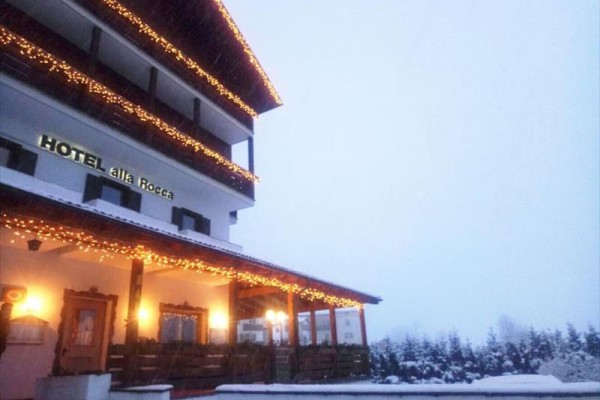 Zasněžená budova hotelu zdobená vánočními světly.