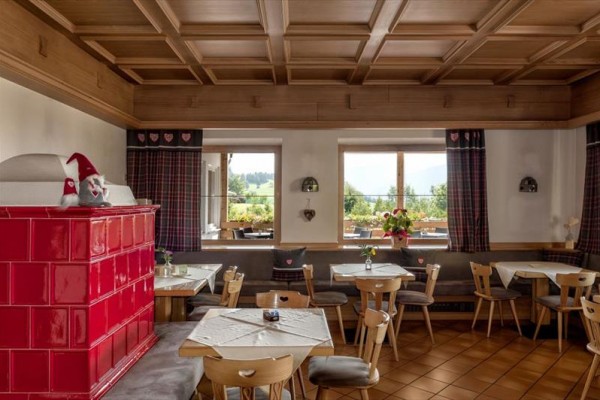 Tradiční interiér restaurace s dřevěným obložením a červenými kachlovými kamny.