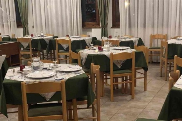 Pokoj se třemi postelemi s červenobílými pruhovanými přehozy pod šikmým stropem.