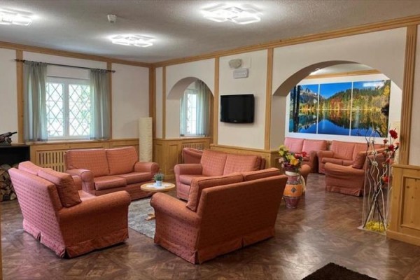 Restaurace se stoly s bílými a zelenými ubrusy připravená na večeři.  