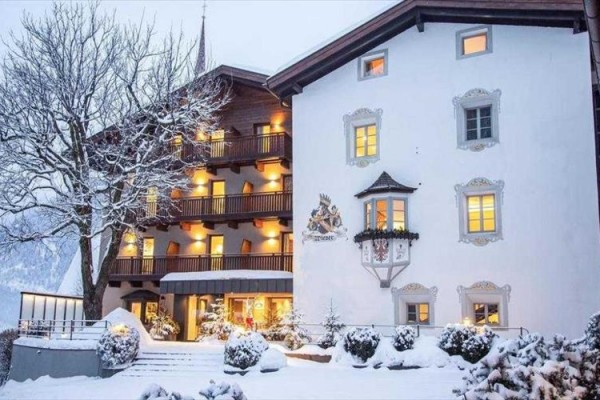 Zasněžený hotel při západu slunce se rozsvícenými okny.
